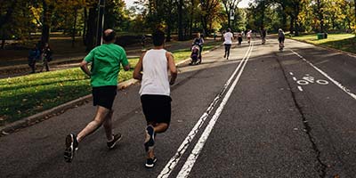Two joggers running on a road in a park