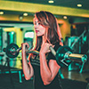 Woman curling weights and bar inward at the gym