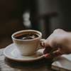 A hand handing over a cup of coffee