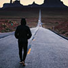 Man walking on a road toward mountains