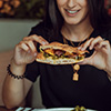 A woman holding a sandwich and smiling