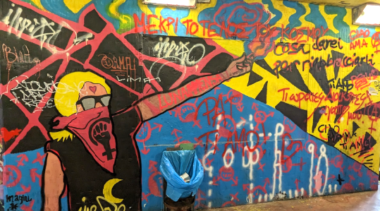 A graffiti mural of a woman with sunglasses and a bandanna, holding a lit match.