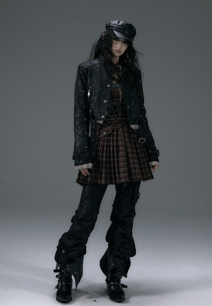 woman wearing a leather jacket, plaid mini dress, and leather black pants with boots