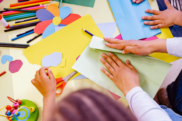 Table of art supplies being used by children.