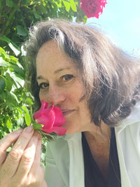 Brown haired woman smelling a pink rose