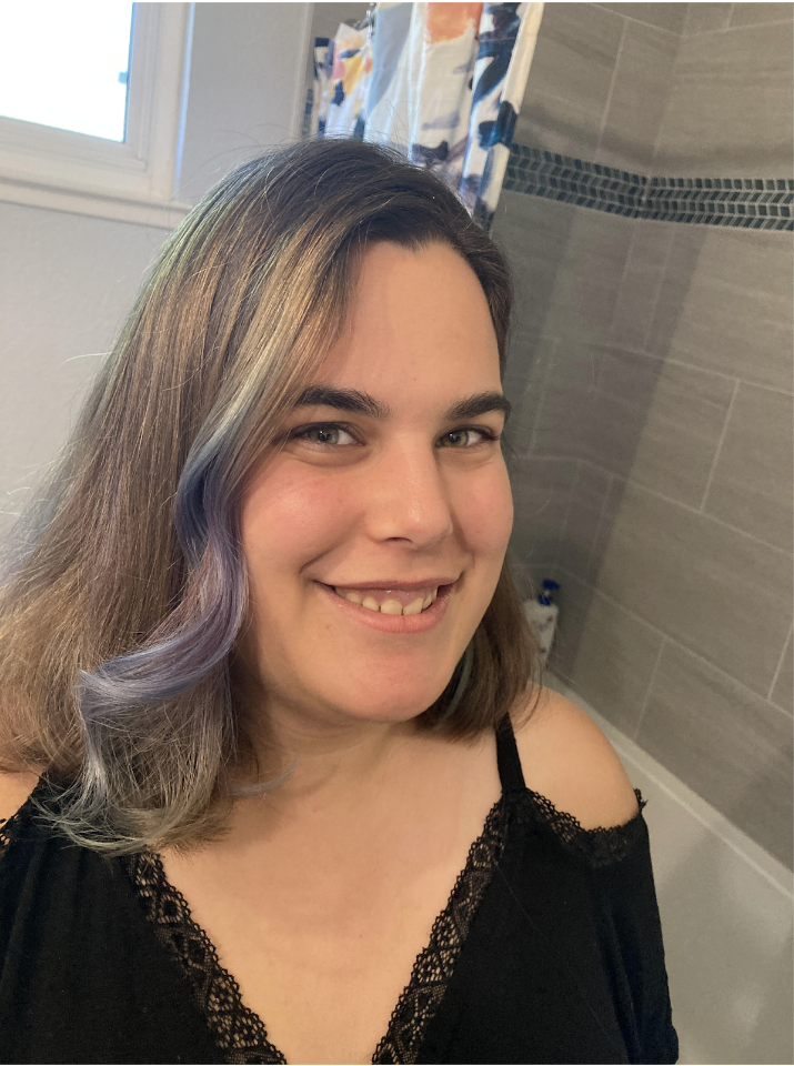 Pudgy girl with brown and lavender colored hair smiling in a black blouse.