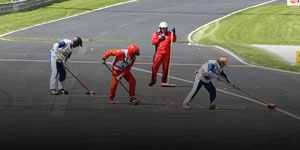 Photo of four people sweeping up small debris on the track