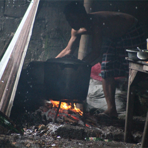 man cooking with large pot in rain storm