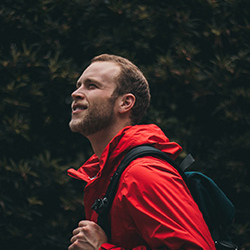 Man in forest with red jacket smiling portrait 