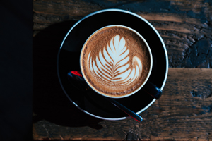 An aerial view of a cup cappuccino with a feather foam art on the top.