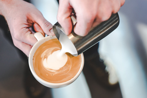A barista pours cream into one of our lattes to make latte art.