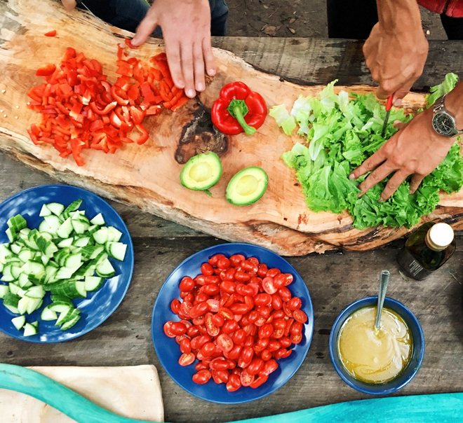 chopped colorful vegetables, avocado and dressing/sauce being prepared