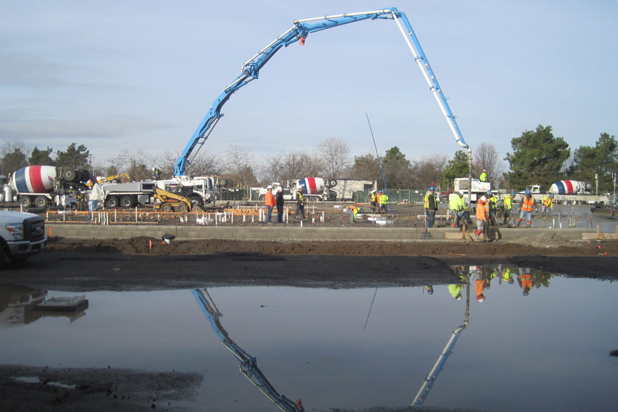 Picture of a concrete boom pump and a pour crew, pouring a multifamily foundation for UC Construction in Merced