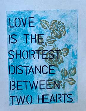 Print of gold roses with text 'love is the shortest distance between two hearts' on blue background.