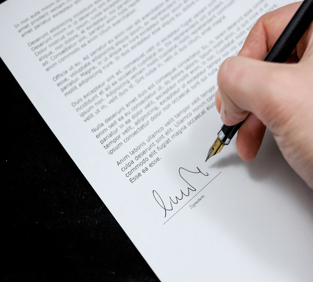 Person signing document with pen