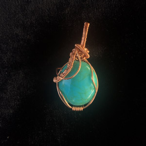 Turquoise stone pendant wrapped in copper wire.
