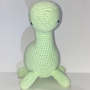 Green crocheted dinosaur plush.