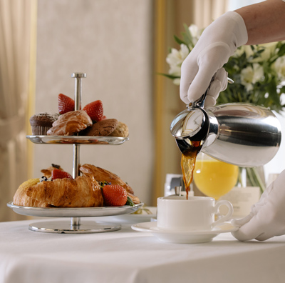 Hotel room service breakfast with coffee being poured