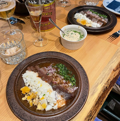 A plating of herring, sauces, and sides with a small glass of vodka