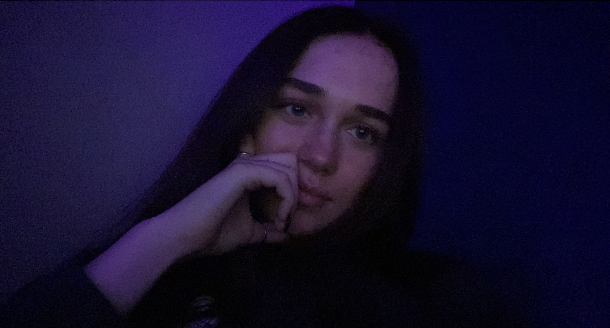 Maycie sitting in her room with purple led lights reflecting off the walls