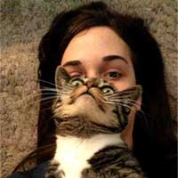 selfie laying on floor, holding tabby cat in front of face