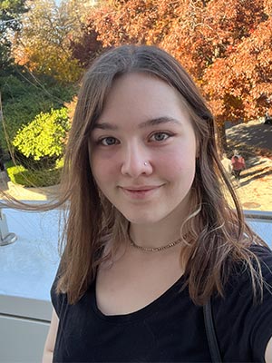 photo of a brunette girl in a black shirt against orange trees