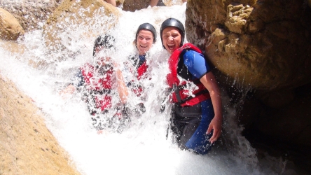 three guest share a smile while being drenched under a waterfall