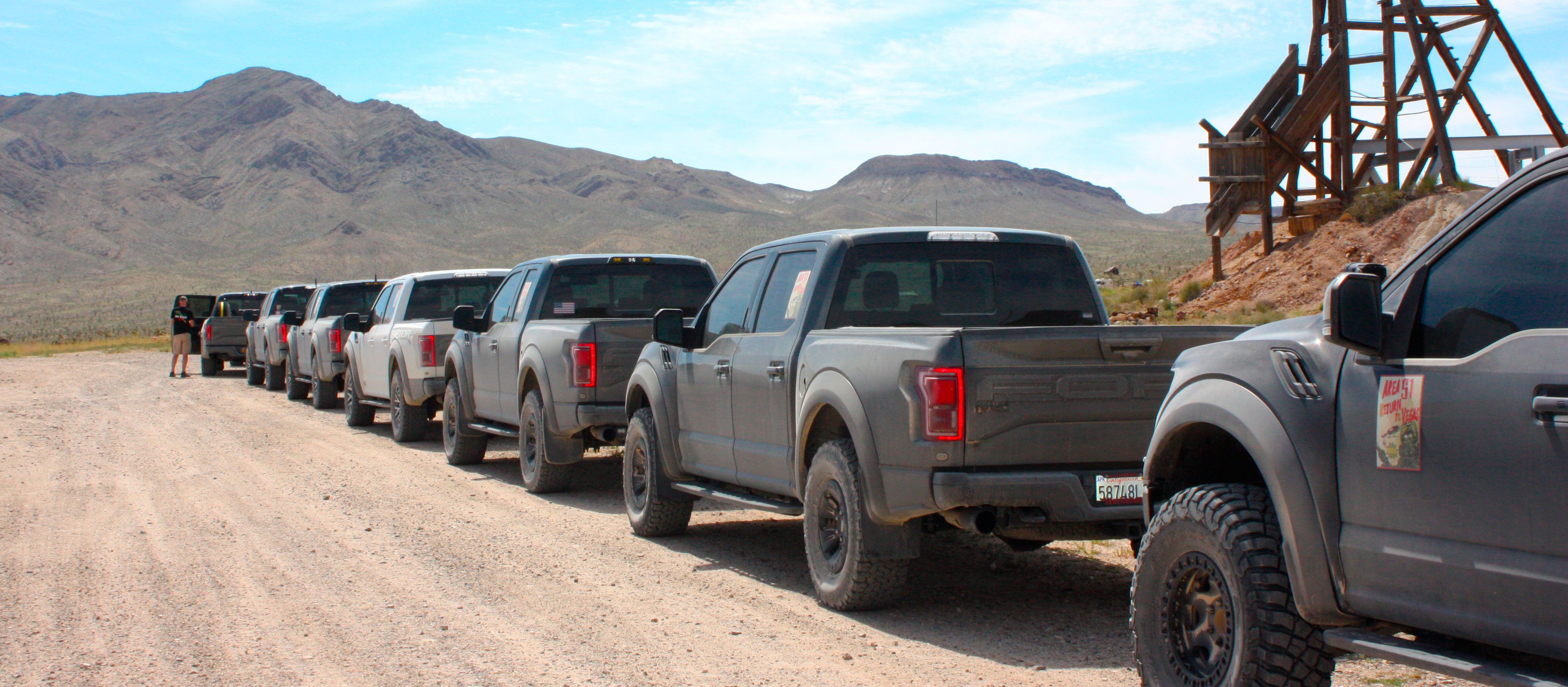 Image of multiple Ford Raptor trucks in a row, in the desert.