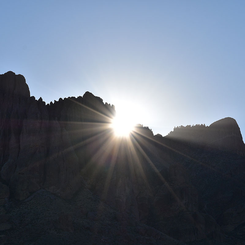 The morning sun peaks through the desert mountain creating sun beams