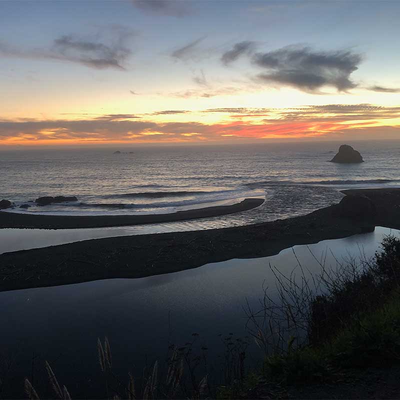The sky turns pink over the waves of the ocean