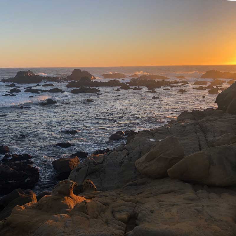 A sunset over the rocky cliffs of the ocean