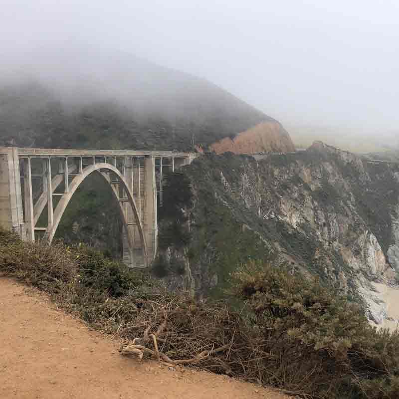 A foggy sky over a giant bridge overlooking the ocean