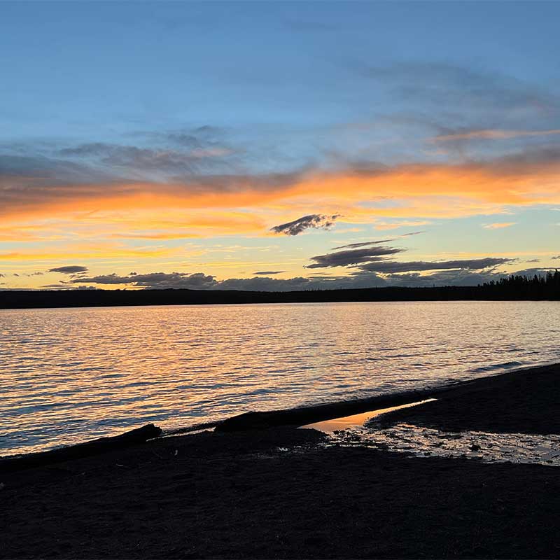 A pink and orange cloudy sky above a gently moving lake