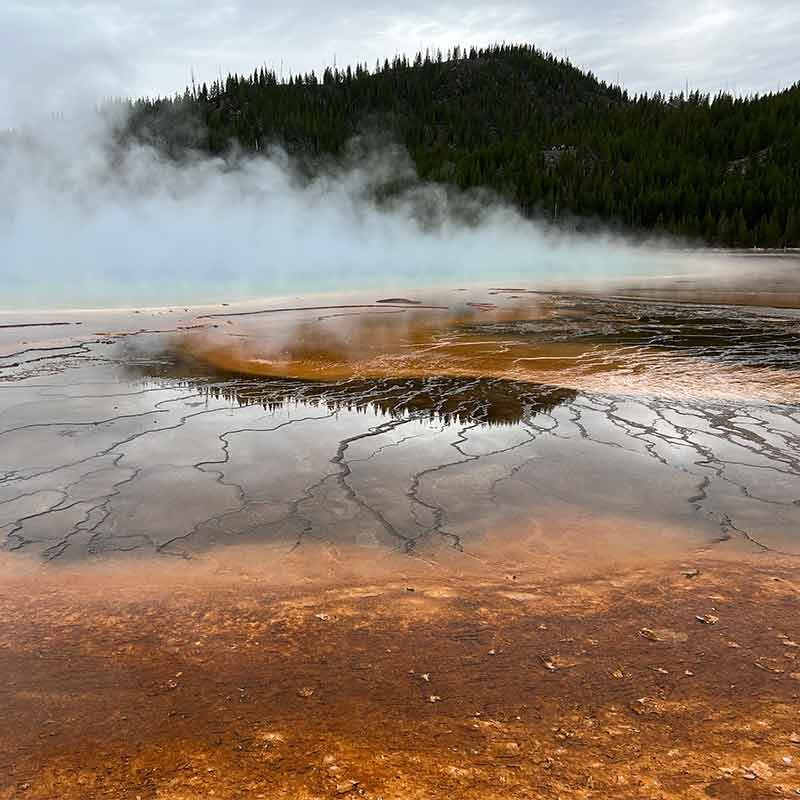 Brown earth layered with hot water cracks emits steam