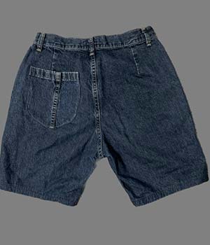 A model wearing dark blue jean shorts that are almost knee length.