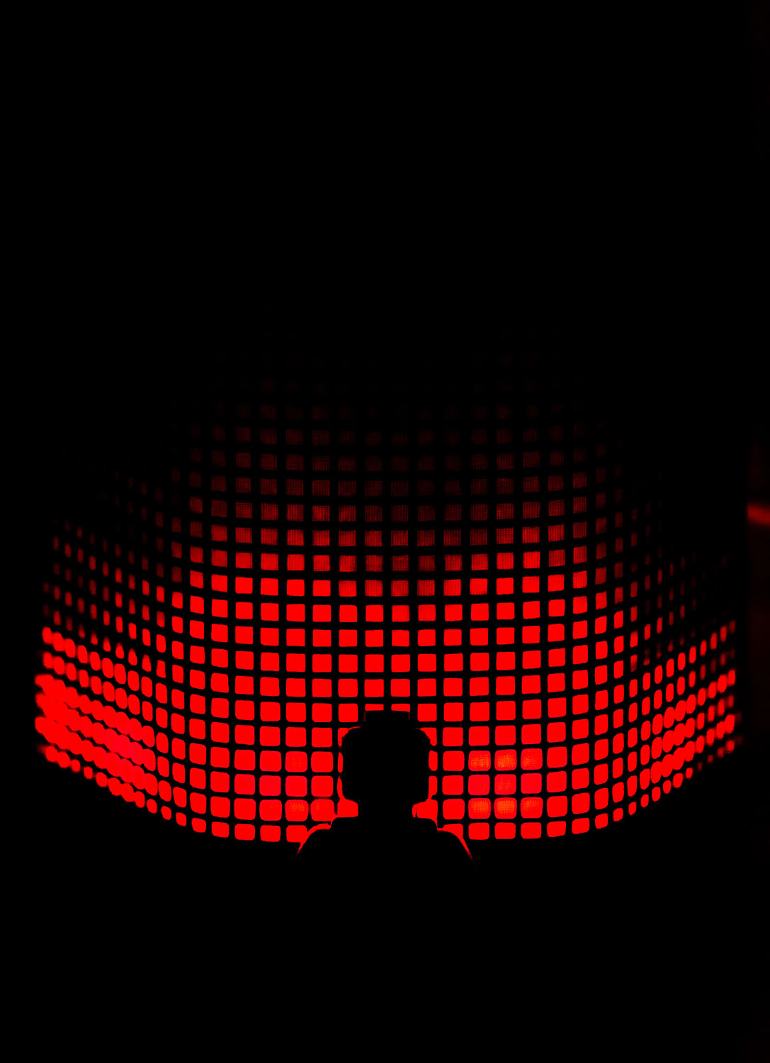 the sillhouette of a person sitting in front of a grid of red dots.