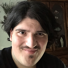 A formal photo of the artist Daniel Vela, smiling at the camera—or perhaps you, the visitor?