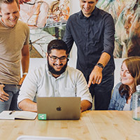 image of a student on his laptop computer surrounded by three other students