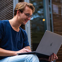 image of a student on his laptop computer surrounded by three other students