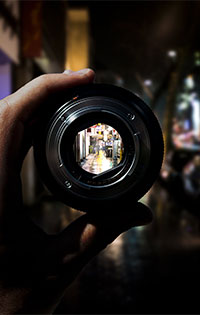 A camera lens reflecting the night-life on a street