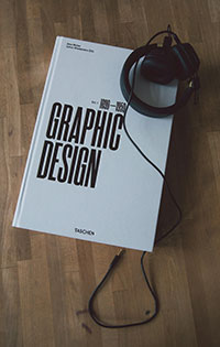 A white book titled Graphic design with black headphones laying on top