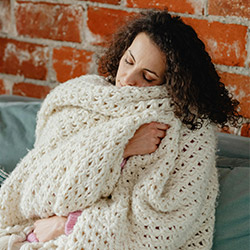 Woman snuggled up on a couch with a crochet blanket