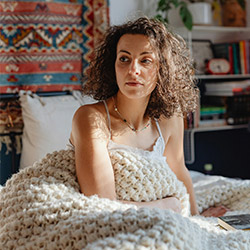 Woman cuddling up with a white crochet blanket