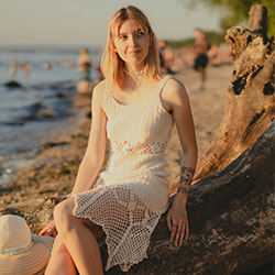 Woman sitting on the beach wearing a white crochet dress
