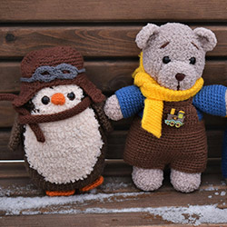 Two small crochet stuffed animals, a bear and a penguin