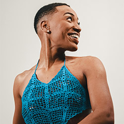 Woman smiling wearing a blue crochet halter top