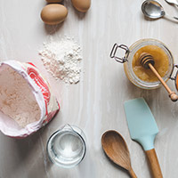 baking flour, eggs,wooden spoon,spatula and honey jar
