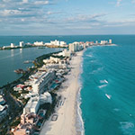 Picture of a view in Cancun, Mexico, and shows buildings and a massive beach and ocean