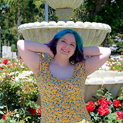 Young girl standing amidst a flower garden and a fountain