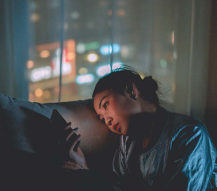 Young girl looks at her phone in the dark.